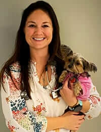 A photo of Dr. Katy LeVon with a small dog in her arms.